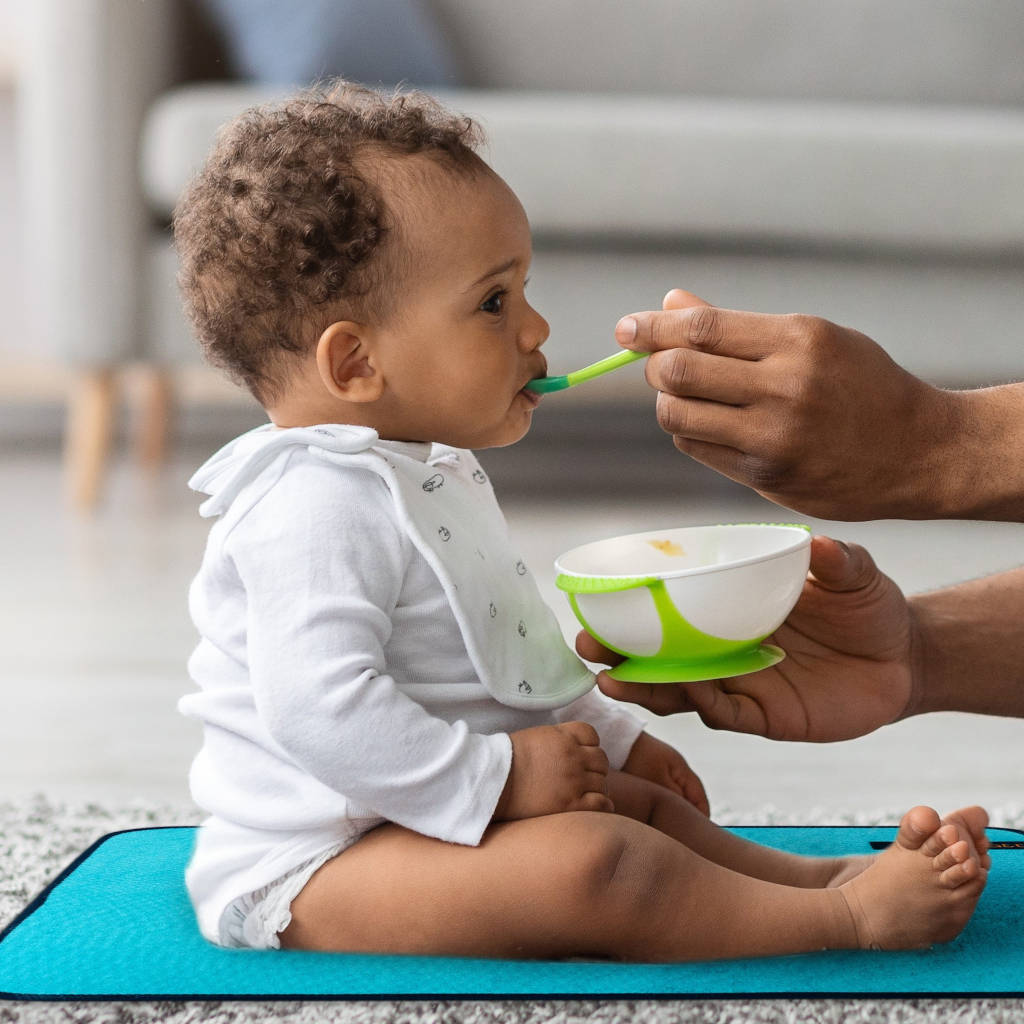 baby sitting on lightweight change mat being fed