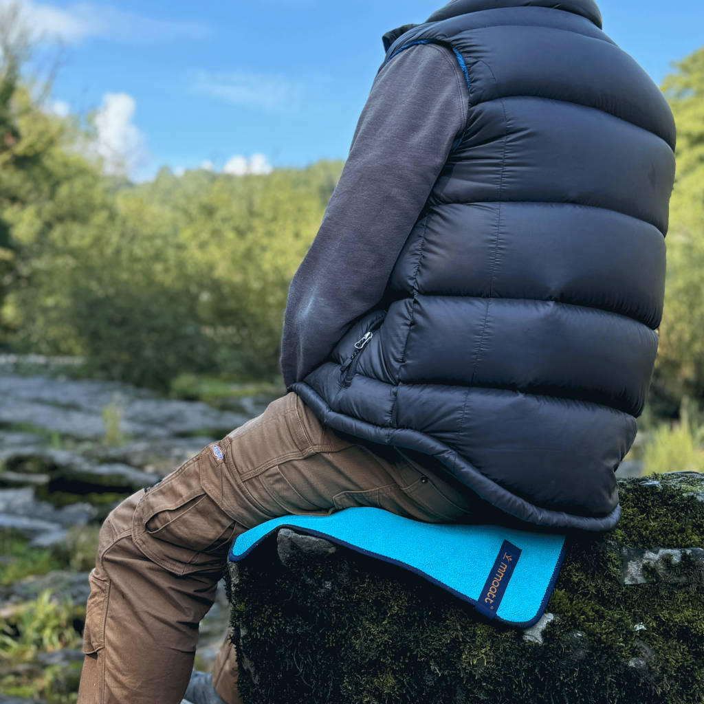 man sitting outdoors on a rock on a thermal and waterproof mat